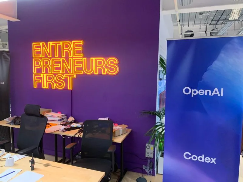 The Entrepreneurs First neon sign on a purple wall, next to an OpenAI Codex banner