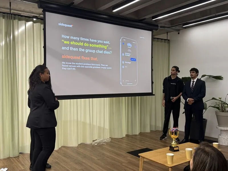 The Sidequest team at the front of the room, with the opening slide asking how many times you have said we should do something and then the group chat dies